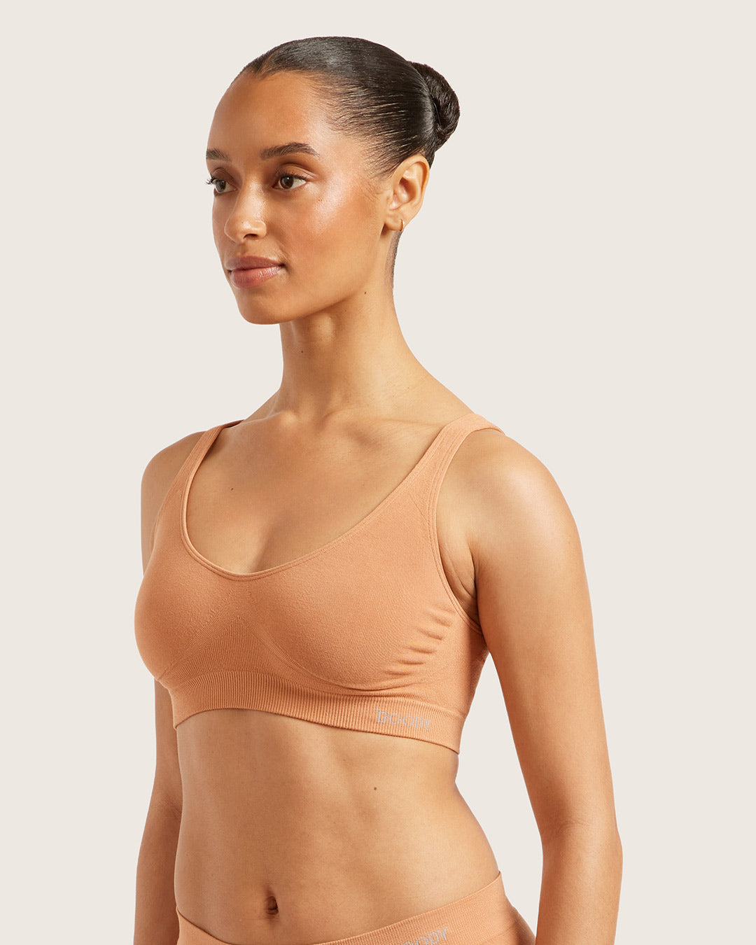 Woman wearing a light brown bra against a light background