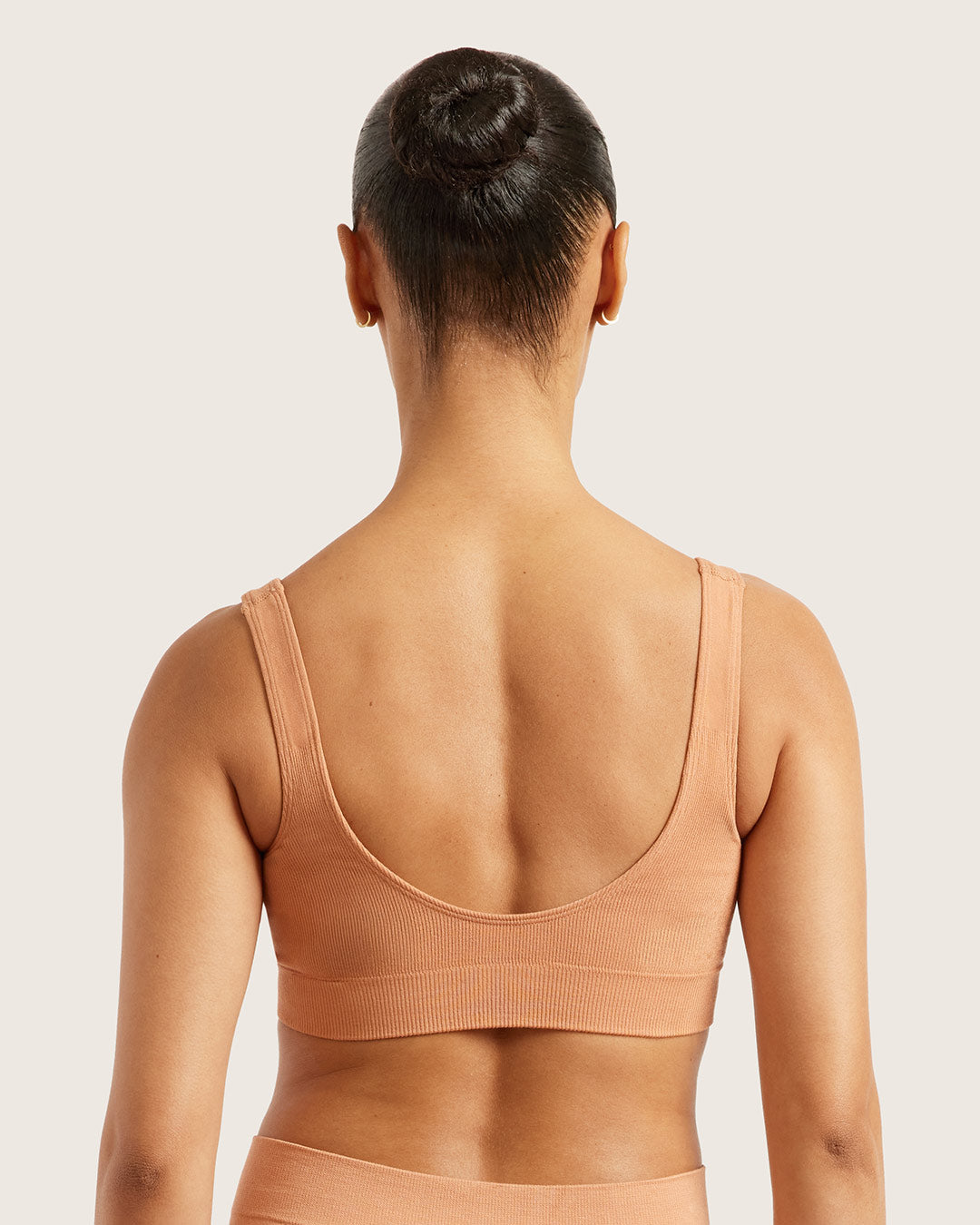 Person wearing a beige crop bra on a plain background