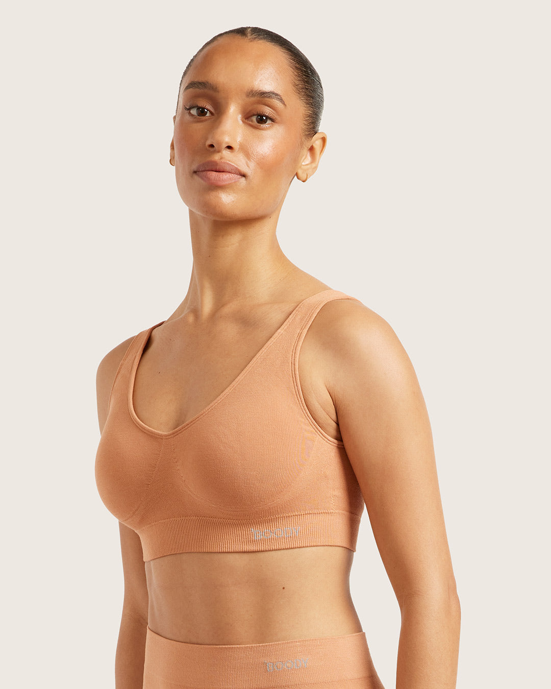 Woman wearing a beige bra on a light background