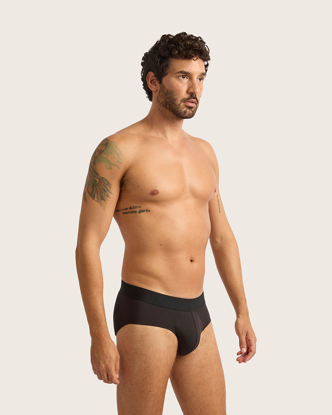 Man wearing black underwear against a plain background