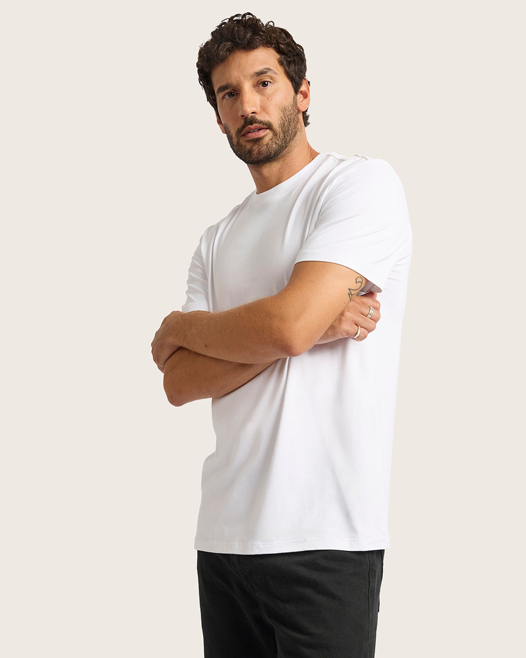 Man wearing a white t-shirt and black pants against a plain background