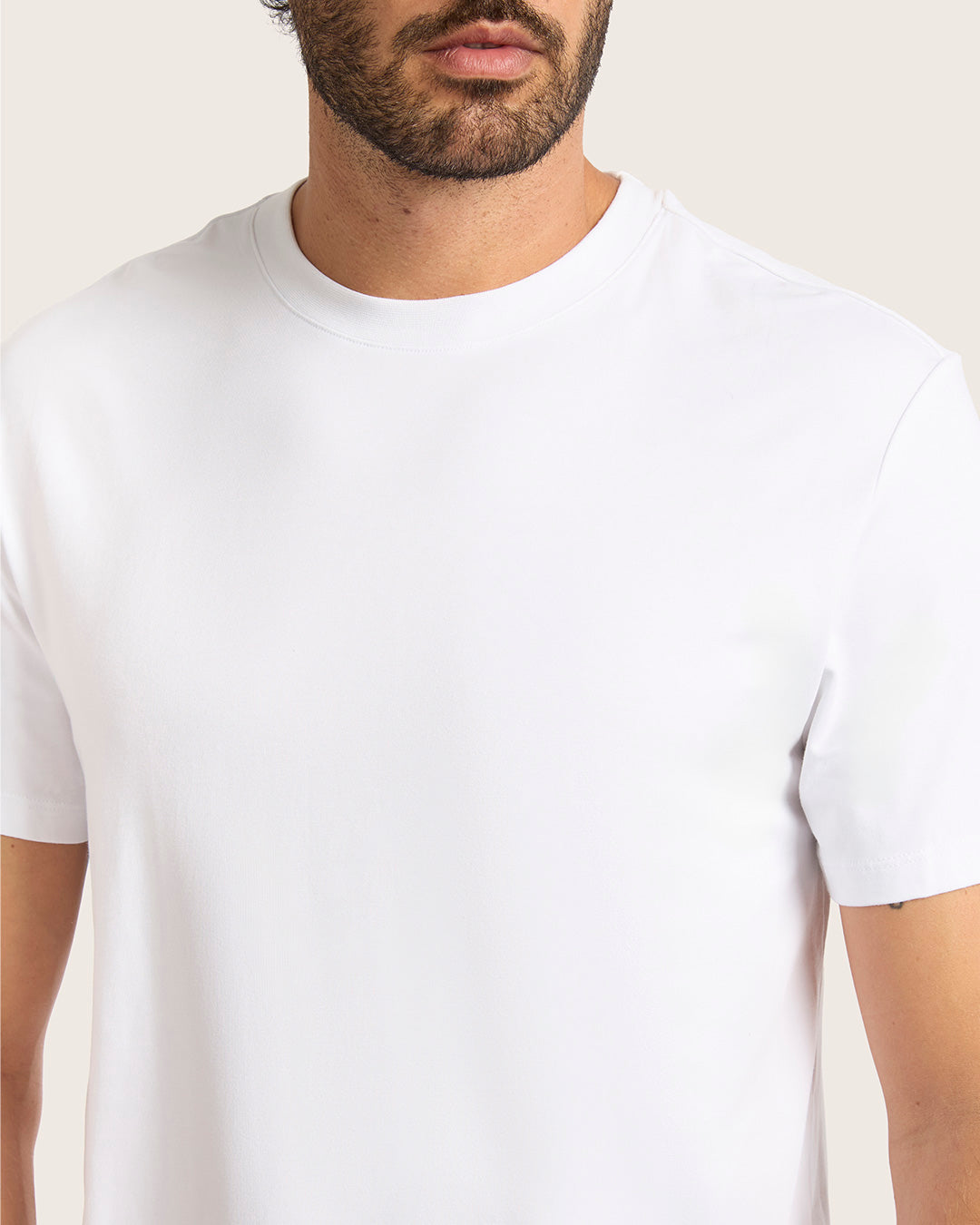 Man wearing a plain white t-shirt against a light background