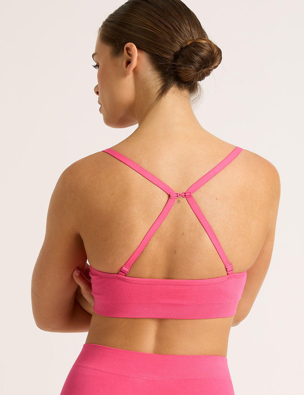 Woman wearing a pink racerback bra on a light background