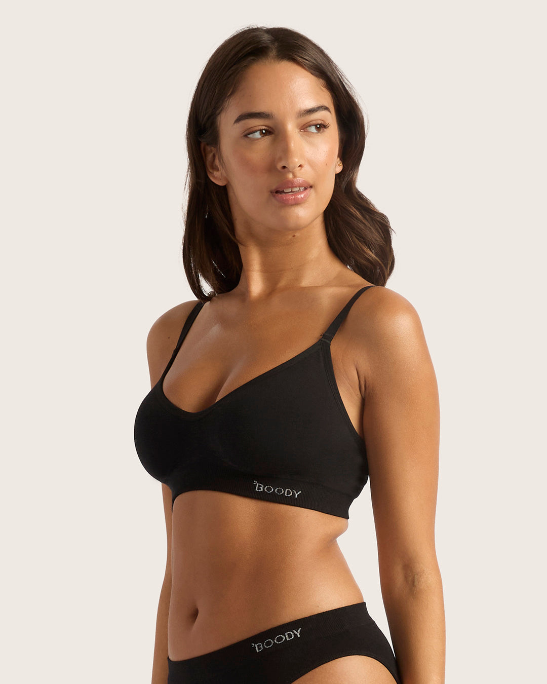 Woman wearing a black bra and panties set with 'Boody' branding on a light background