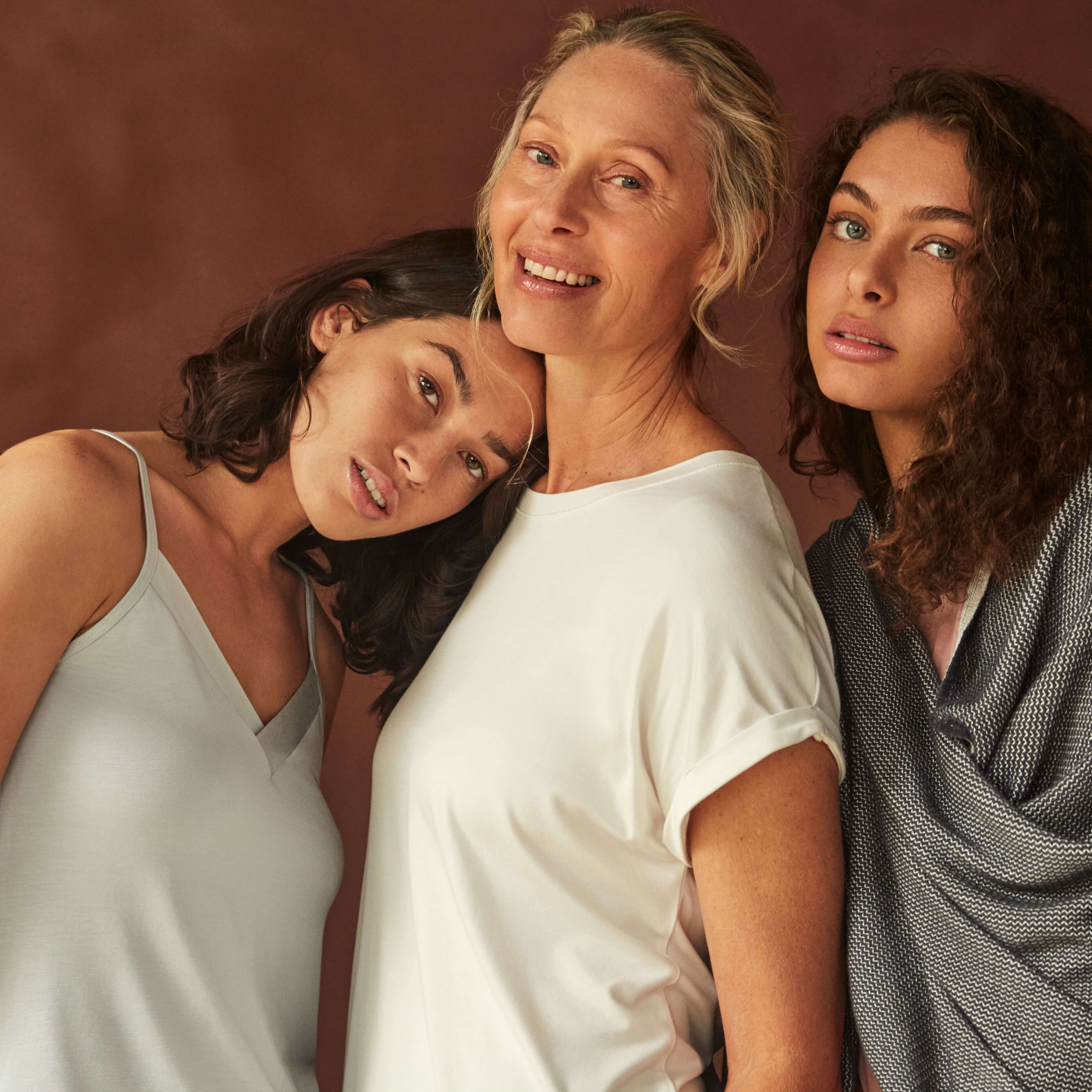 Three women posing together against a brown background