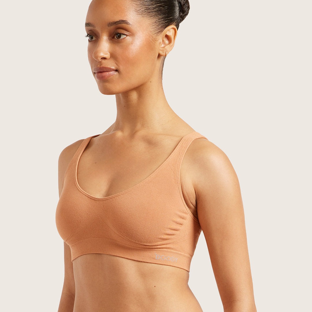 Woman wearing a light brown bra against a light background