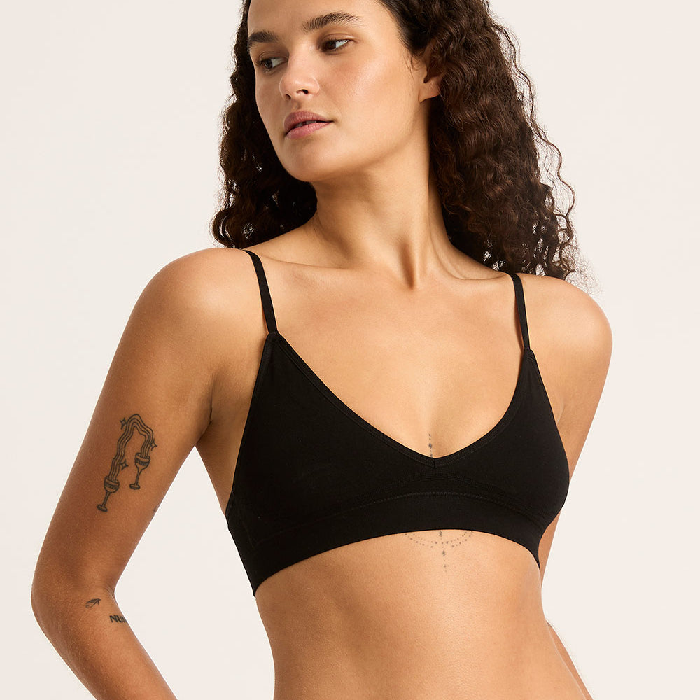 Woman wearing a black bralette against a plain background