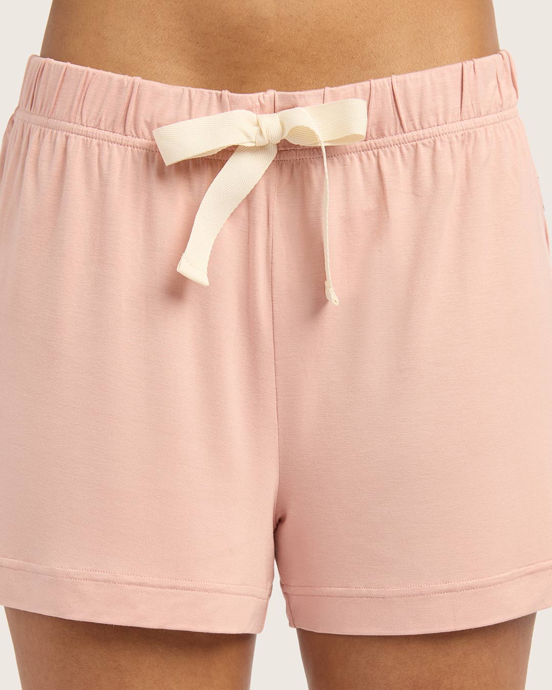 Pink shorts with a white drawstring on a plain background