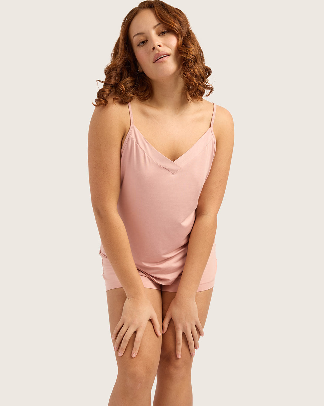 Woman wearing a pink pj set on a plain background