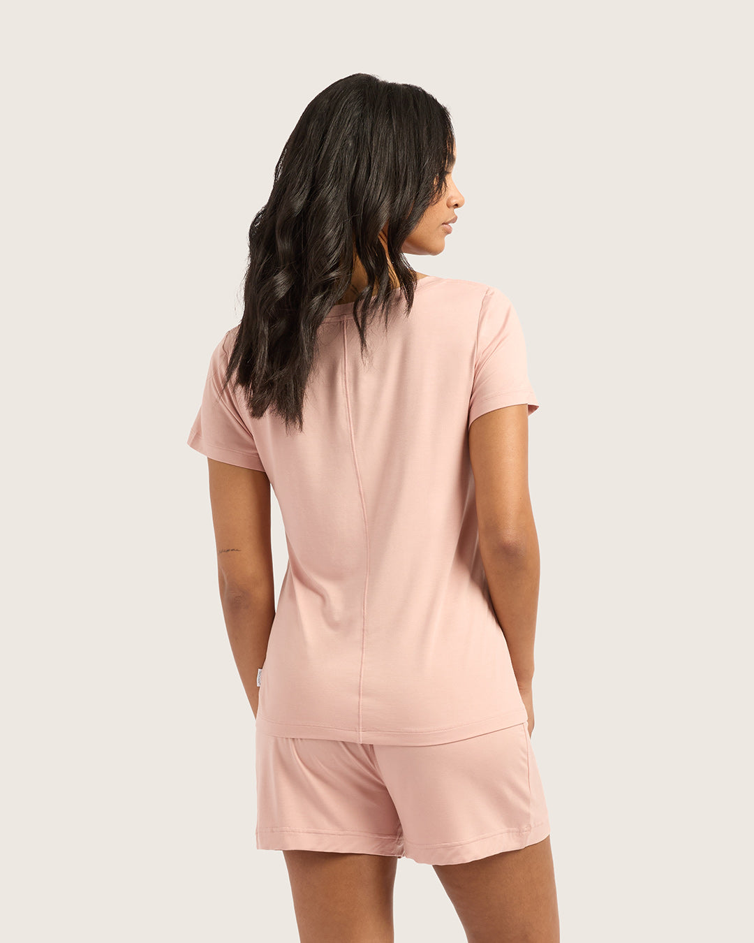 Woman wearing a pink pajama set on a plain background