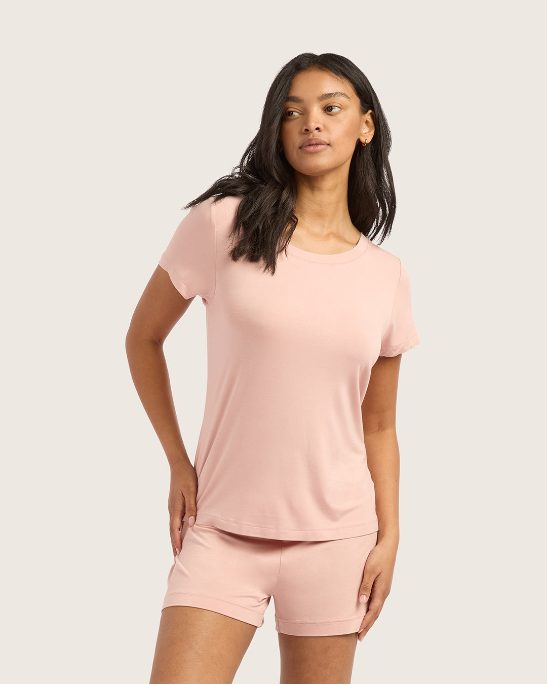 Woman wearing a pink t-shirt and shorts set on a plain background