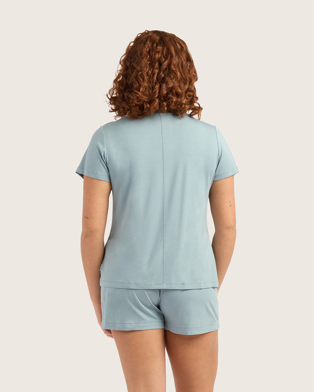 Person wearing a light blue t-shirt and shorts set on a plain background