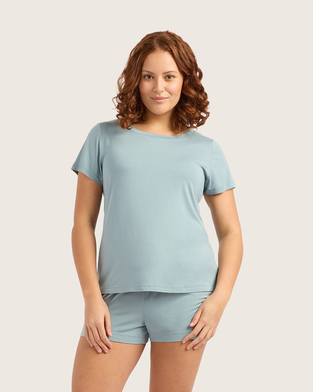 Woman wearing a light blue t-shirt and shorts set on a plain background