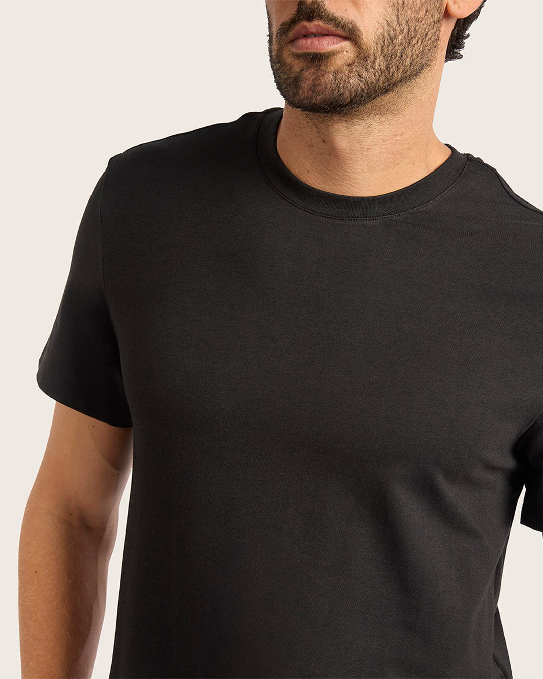 Man wearing a plain black t-shirt against a neutral background
