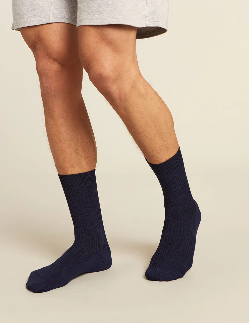 Navy socks worn with a light gray short on a beige background