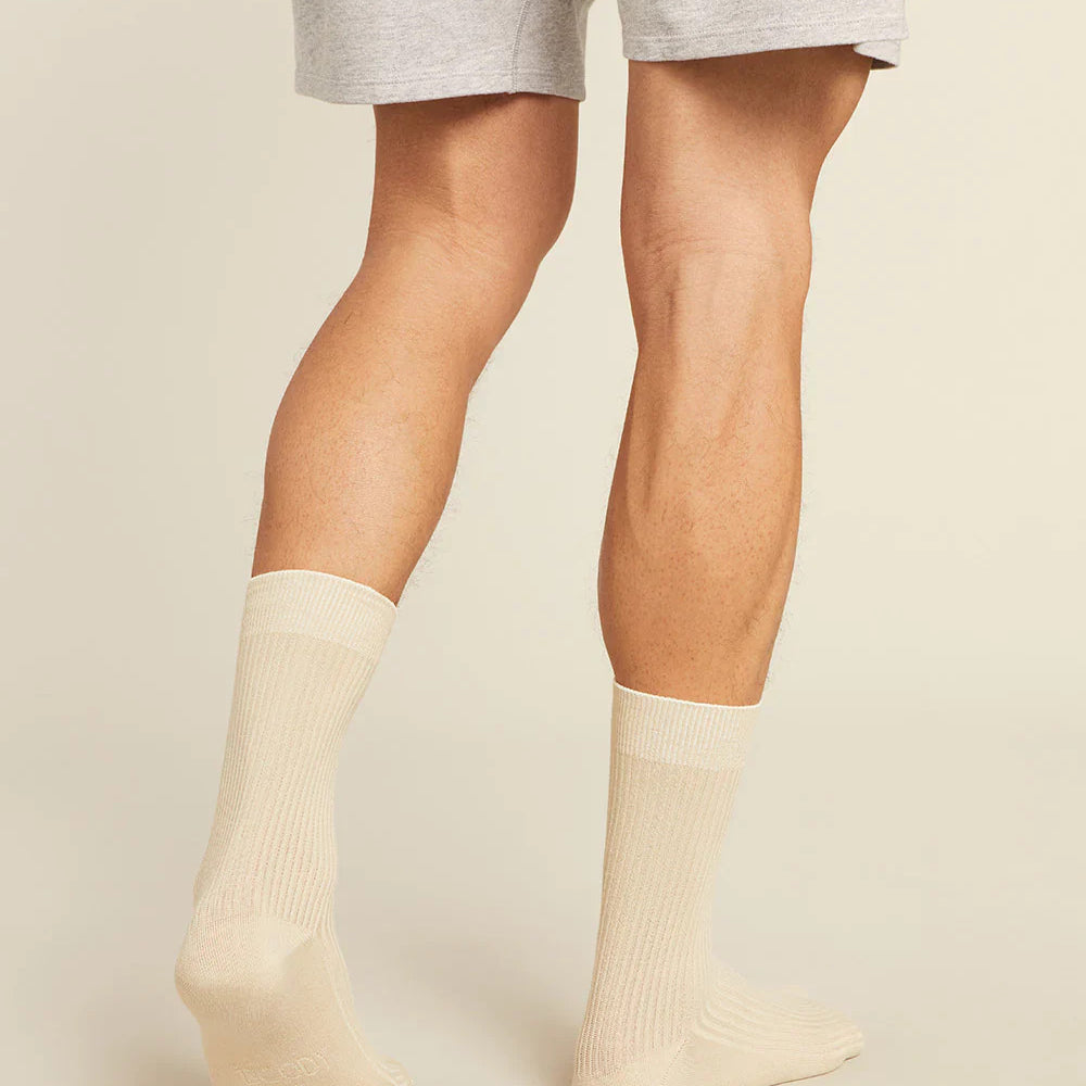 Person wearing beige socks and gray shorts on a plain background