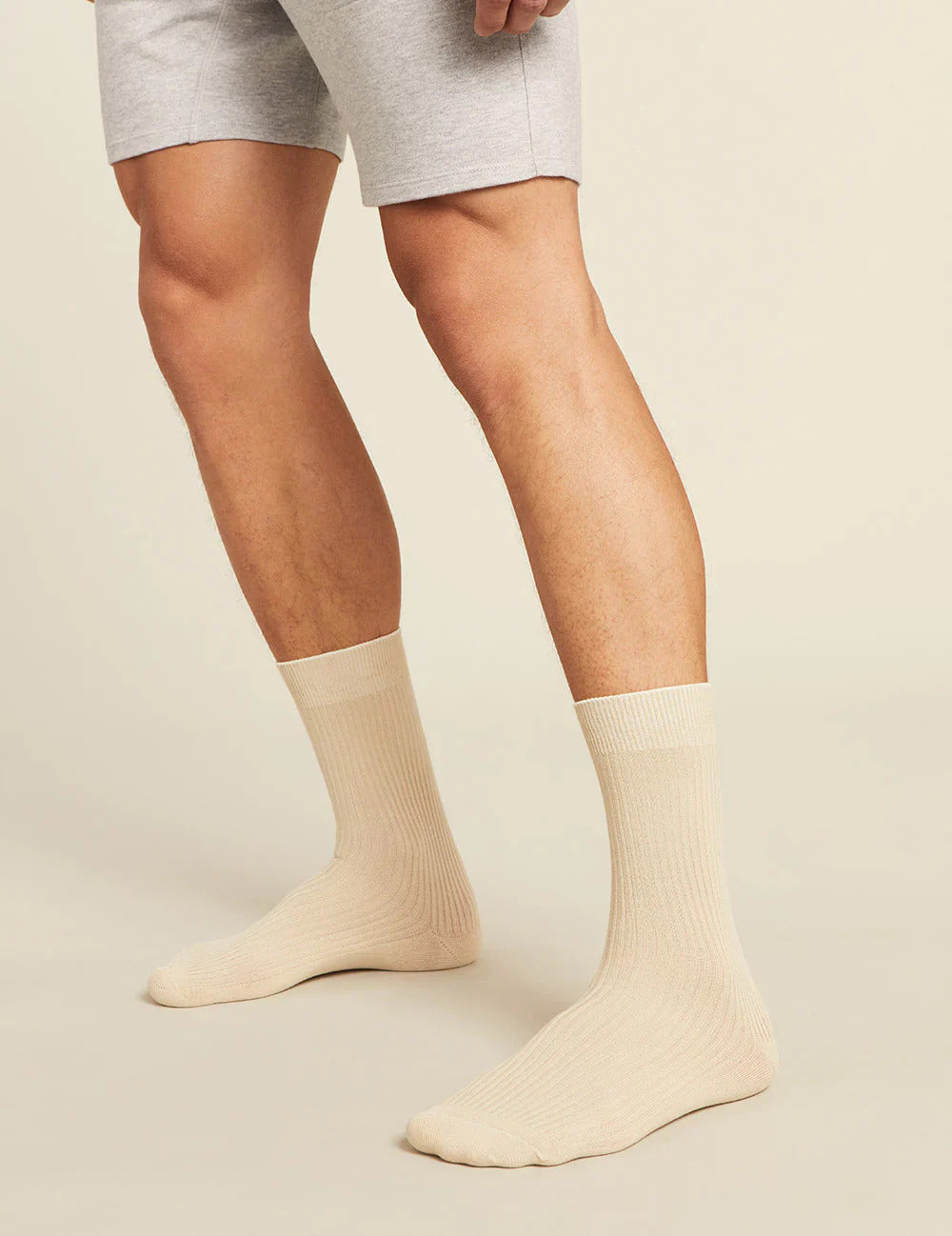 Beige socks worn with gray shorts on a beige background