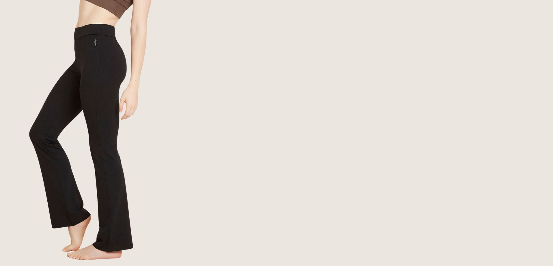 Person wearing black flared pants on a beige background