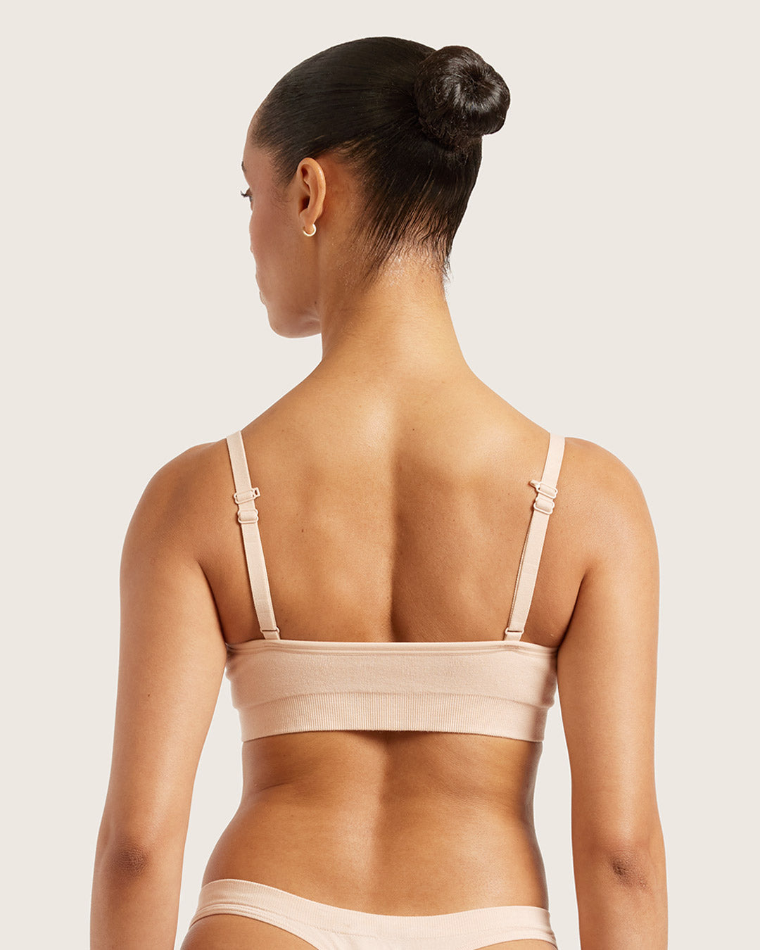 Woman wearing a beige bra and underwear set on a light background