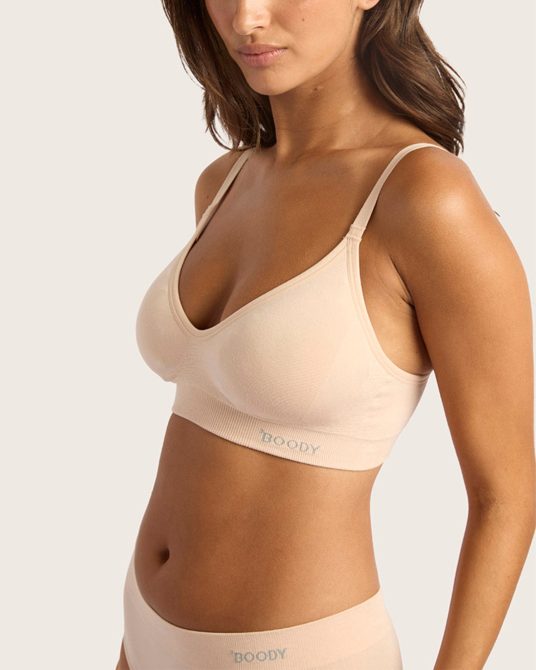 Woman wearing a beige bra with 'BOODY' branding on a light background